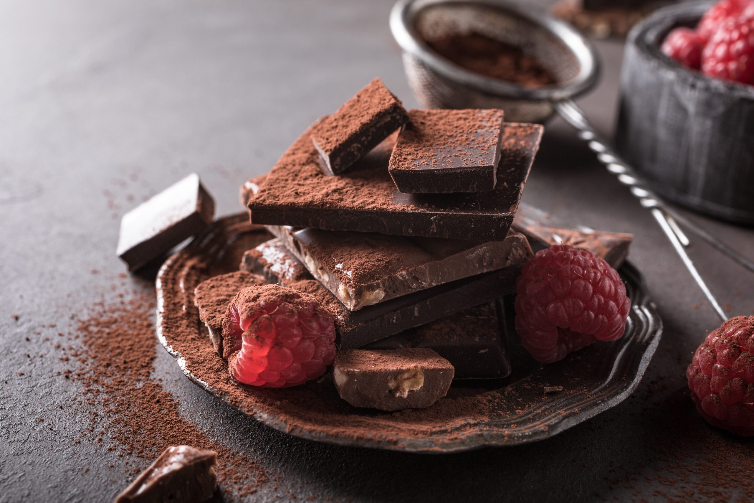 photo with Broken chocolate pieces and raspberries with cocoa powder
